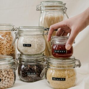 A neat arrangement of labeled glass jars containing beans, rice, and more, in a pantry setting.